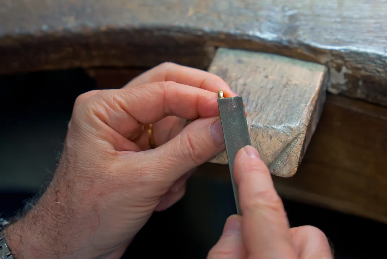 Joaillier de la maison SIAUD limant une alliance en or à l'établi de son atelier à Nice